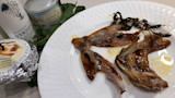Roasted fish tongues on white plate with tin labeled Fleur de sel and bottle labeled VERJUICE