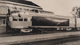Vintage streamlined passenger railcar with large whale mural on its side at a station