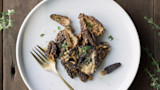 Sauteed morel mushrooms with garlic butter and thyme on white plate, fork