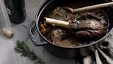 Braised wild game shanks in STAUB pot with rosemary, wine bottle, cork, wooden spoon