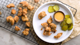 Crispy fried turkey nuggets on a plate with honey mustard dipping sauce and pickles