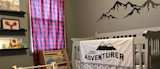 Nursery crib draped with blanket reading little ADVENTURER and mountain wall decal above