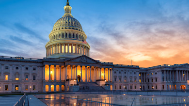 U.S. Capitol dome and lit facade at sunset with reflections on plaza