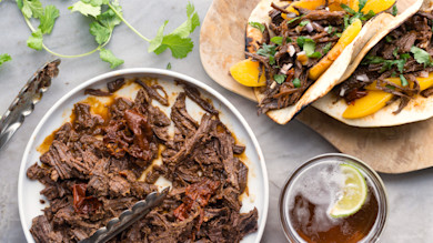 Barbacoa tacos with peach slices and cilantro; bowl of shredded beef and a beer with lime