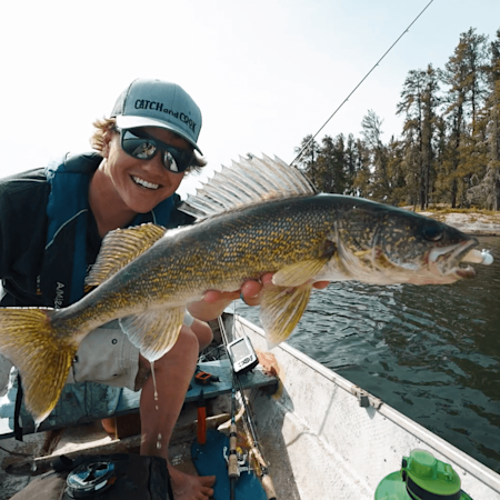 Smiling angler holding large walleye in a boat, cap text "CATCHandCOOK"