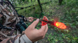 Hunter holding blood-stained arrow with glowing red nock in camo jacket
