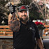 Bearded man in cap holding grilled tomahawk steak by the bone with black glove