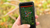 Hand holding smartphone showing satellite map with clustered location pins; top reads OFFLINE
