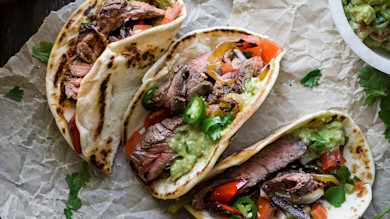 Three venison steak tacos with guacamole, jalapeño, grilled peppers, tomato and cilantro