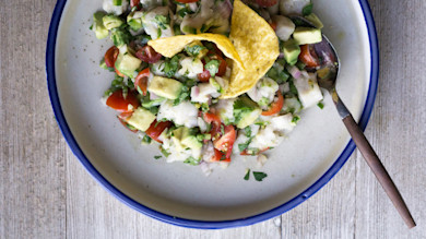 Speckled-trout ceviche with avocado, cherry tomatoes and tortilla chip in bowl with spoon