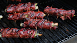 Grilled venison negimaki rolls wrapped around scallions, skewered with toothpicks and charred on grill grate