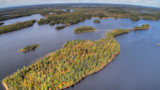 Aerial view of lakes dotted with forested islands and fall foliage