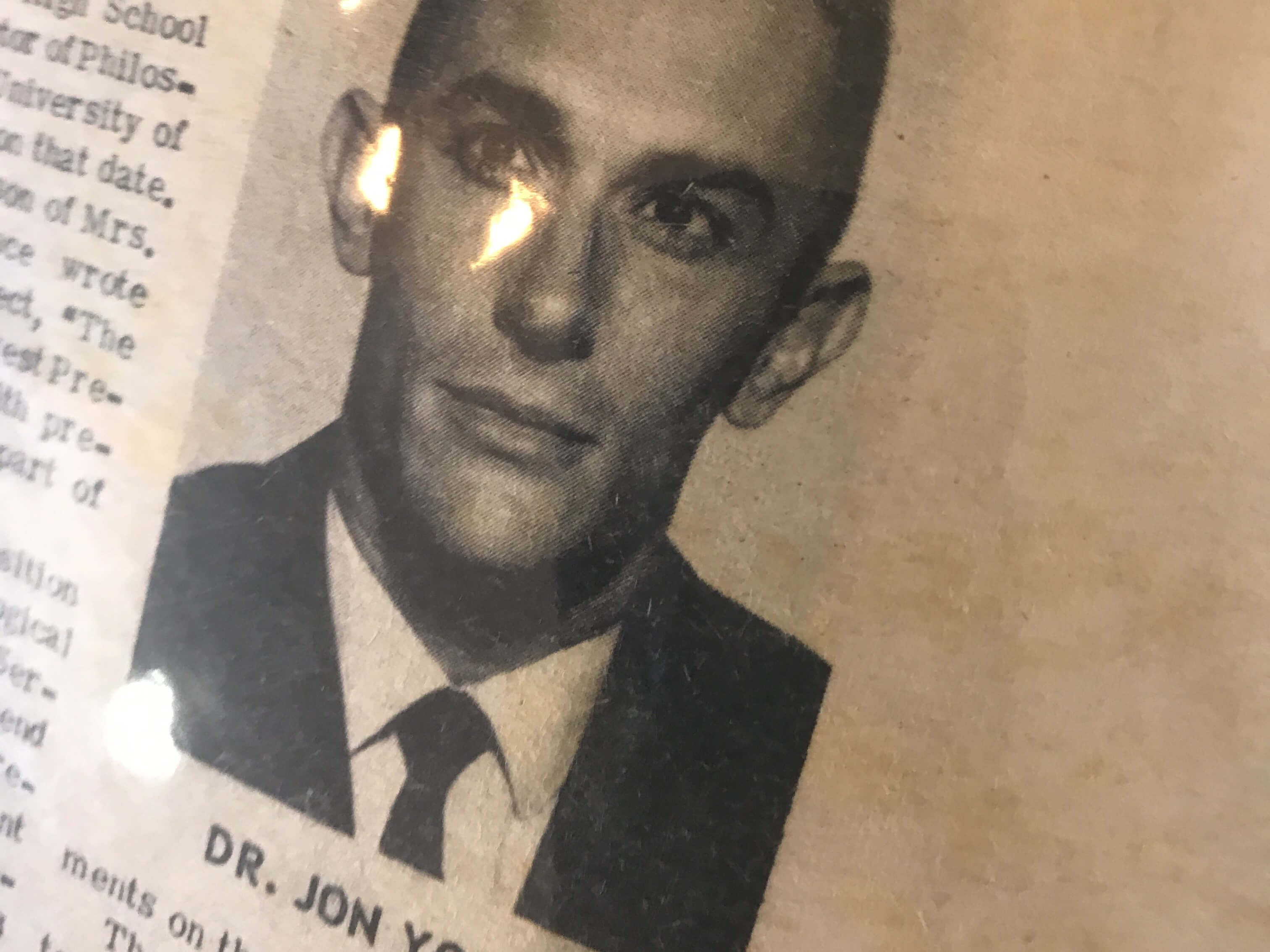 B&W newspaper portrait of man in suit; visible caption text "DR. JON Y"