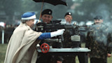 Woman in blue hat and white gloves firing a mounted machine gun as soldiers watch