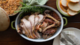 Roasted carved turkey in oval pan with rosemary, stuffing, sliced bread and a serving plate