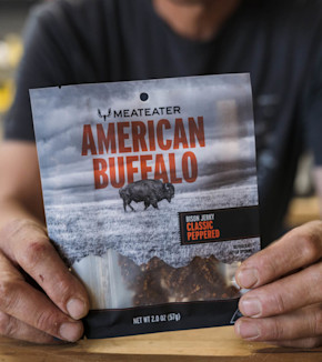 MEATEATER AMERICAN BUFFALO bison jerky bag reading "BISON JERKY CLASSIC PEPPERED" held by a man