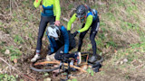 Two cyclists help a fallen rider by a toppled bike and deer in ditch; text "RECYCLED CYCLES" on right leg