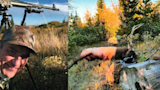 Hunter smiling beside tripod; elk carcass with antlers lying by log in meadow