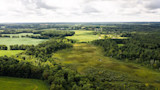 Aerial view of patchwork farm fields and surrounding woodlots under cloudy sky