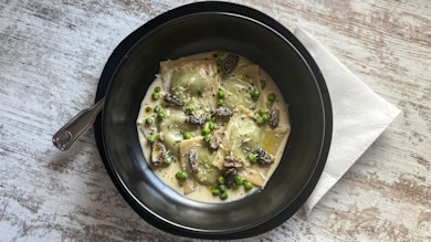 Ravioli in creamy sauce with peas, foraged morel mushrooms, grated cheese and olive oil
