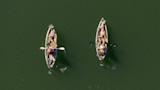 Aerial view of two kayaks each carrying a hunter and a harvested buck on green water