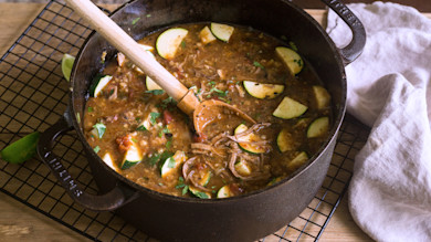 Southwestern turkey soup in cast-iron pot with zucchini, shredded turkey and wooden spoon