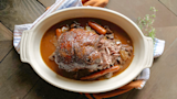 Shredded roast with carrots, mushrooms, onions and thyme in gravy in white oval baking dish