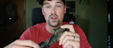 Man holding camouflage turkey call and speaking to camera