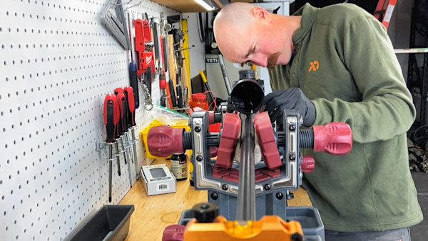 Man mounting rifle scope on rifle held in a bench vise in a workshop