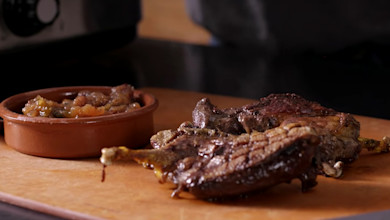 Seared duck breasts on wooden cutting board with small brown dish of fruit chutney