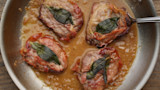 Four venison saltimbocca medallions in skillet with fried sage and pan sauce