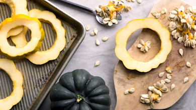 Acorn squash rings and seeds on a baking sheet and wooden cutting board