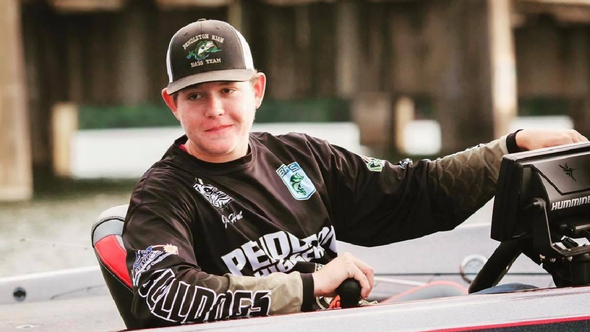 Young man steering a bass boat, cap reads "Pendleton High Bass Team"