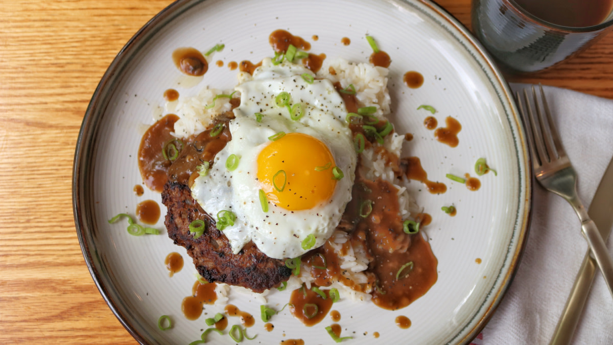 Seared venison patty on rice with brown gravy, sunny-side egg and sliced scallions