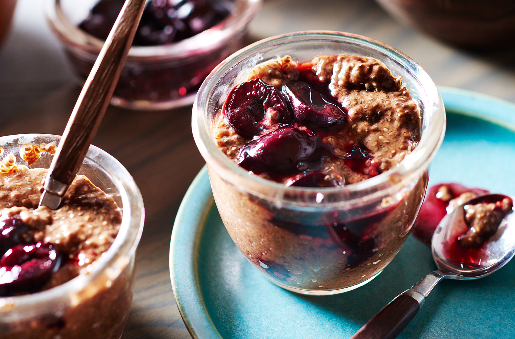 A jar filled with chocolate cherry chia pudding topped with cherries