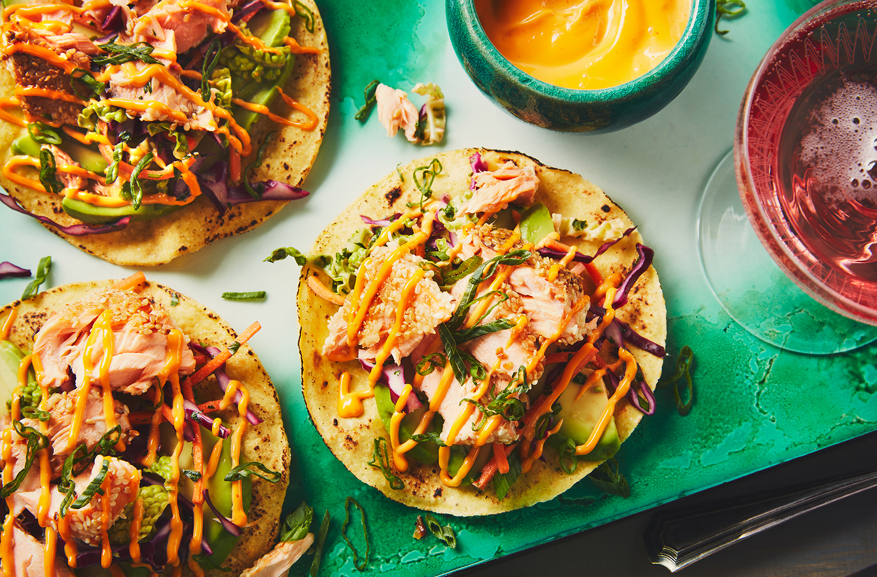 Three tostadas topped with salmon, coleslaw and sriracha mayo