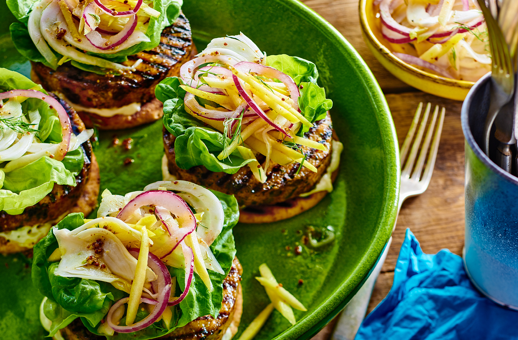 4 open-faced salmon burgers atop naan rounds topped with lettuce and shaved apples and fennel