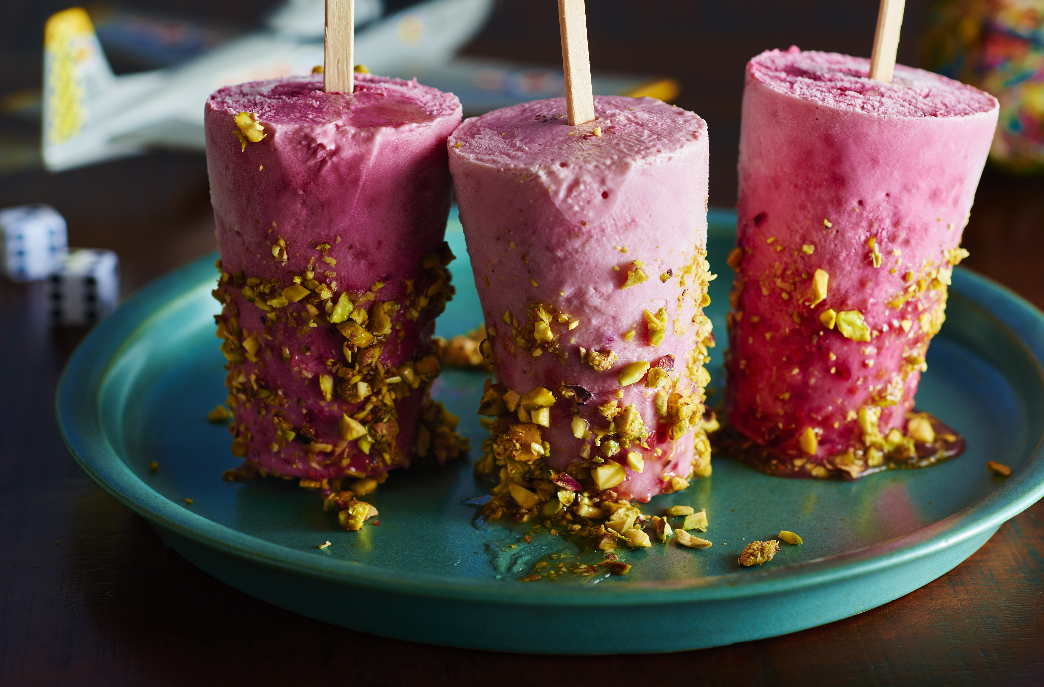 A platter of strawberry-raspberry skyr popsicles coated with pistachios
