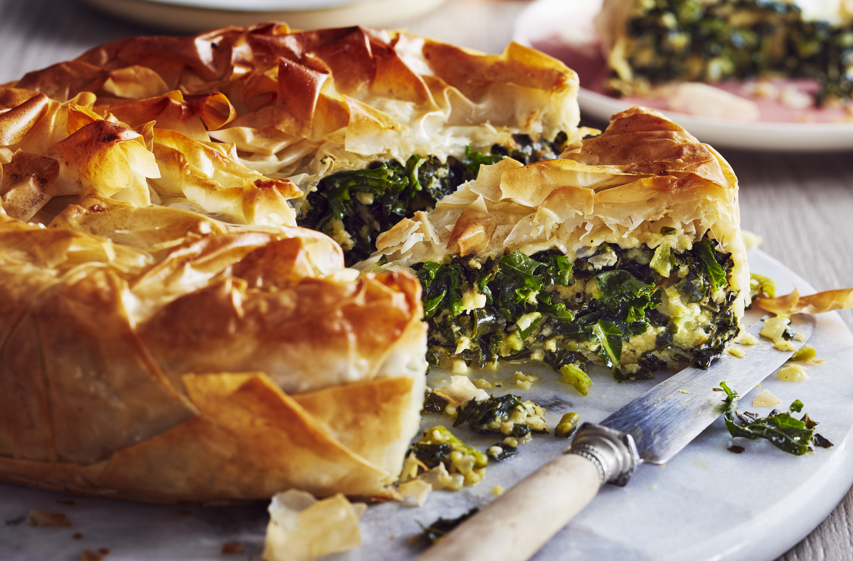 Flaky pastry encloses kale and feta in a pie shape, with one slice cut out