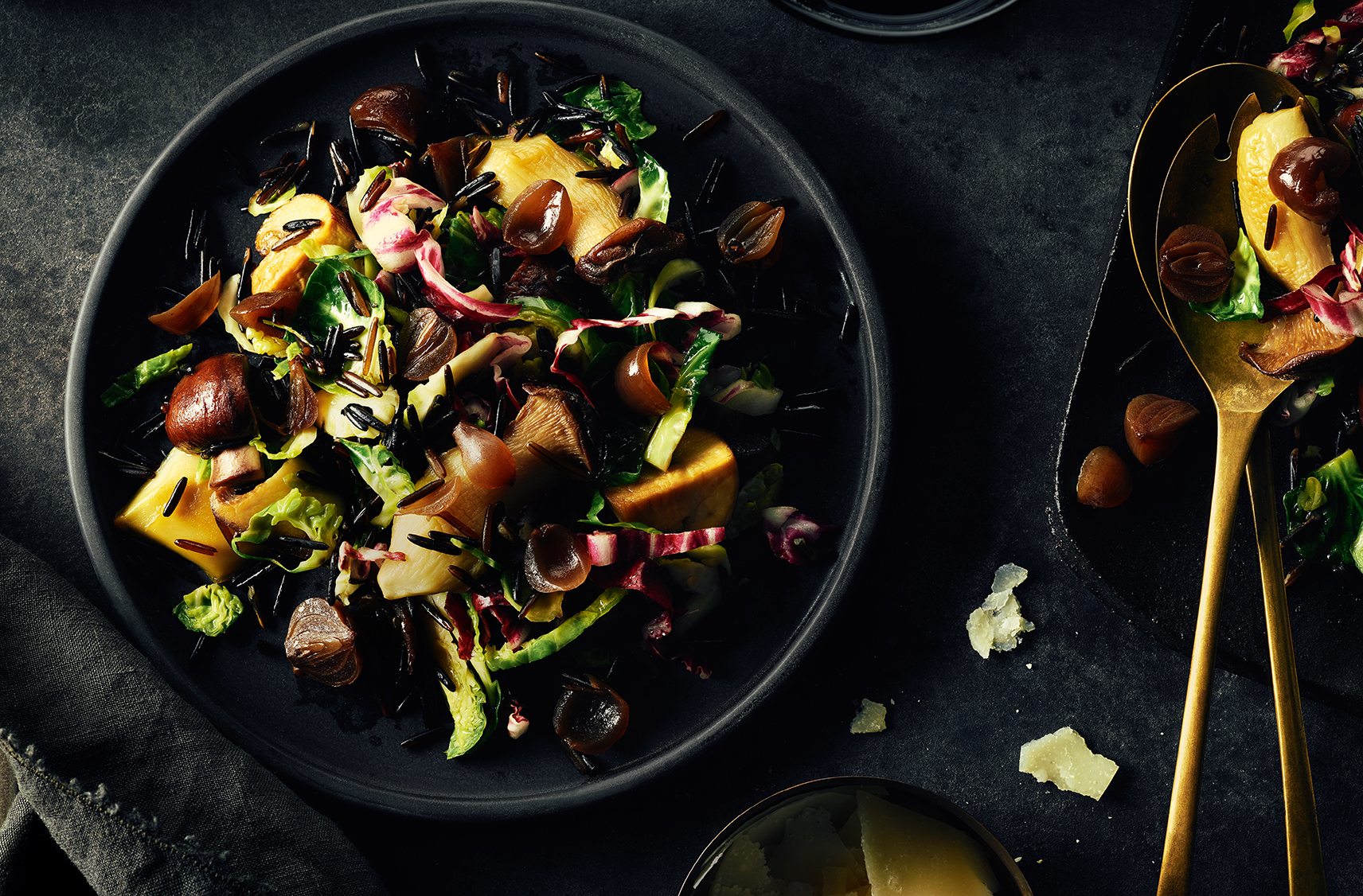 A salad of radicchio, greens, mushrooms, onions and rice fills a black bowl.
