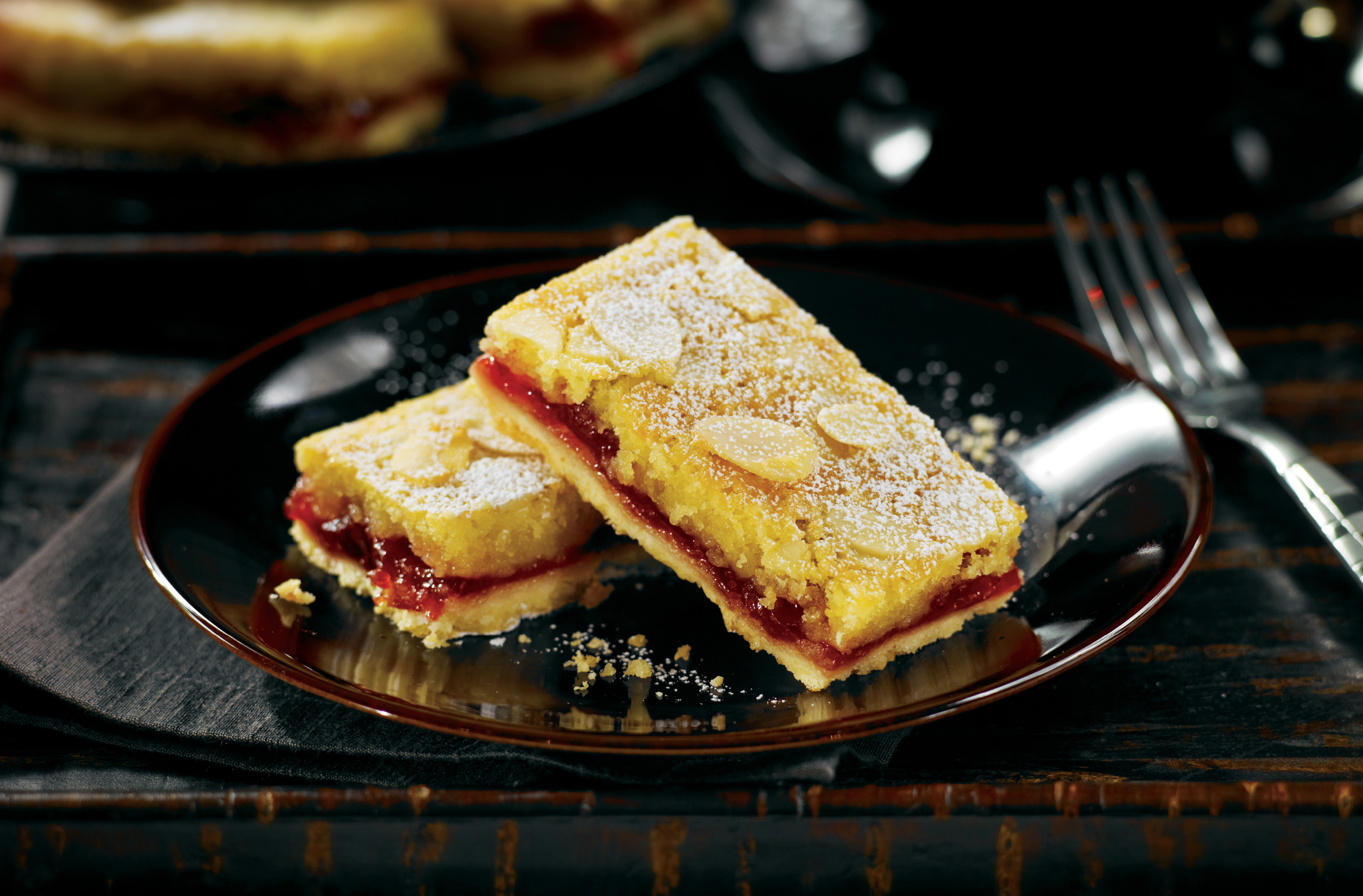 2 dessert squares with cherry centre topped with almond slices
