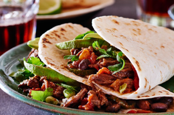 Two soft tortillas filled with seasoned strips of stewing beef and veggies.