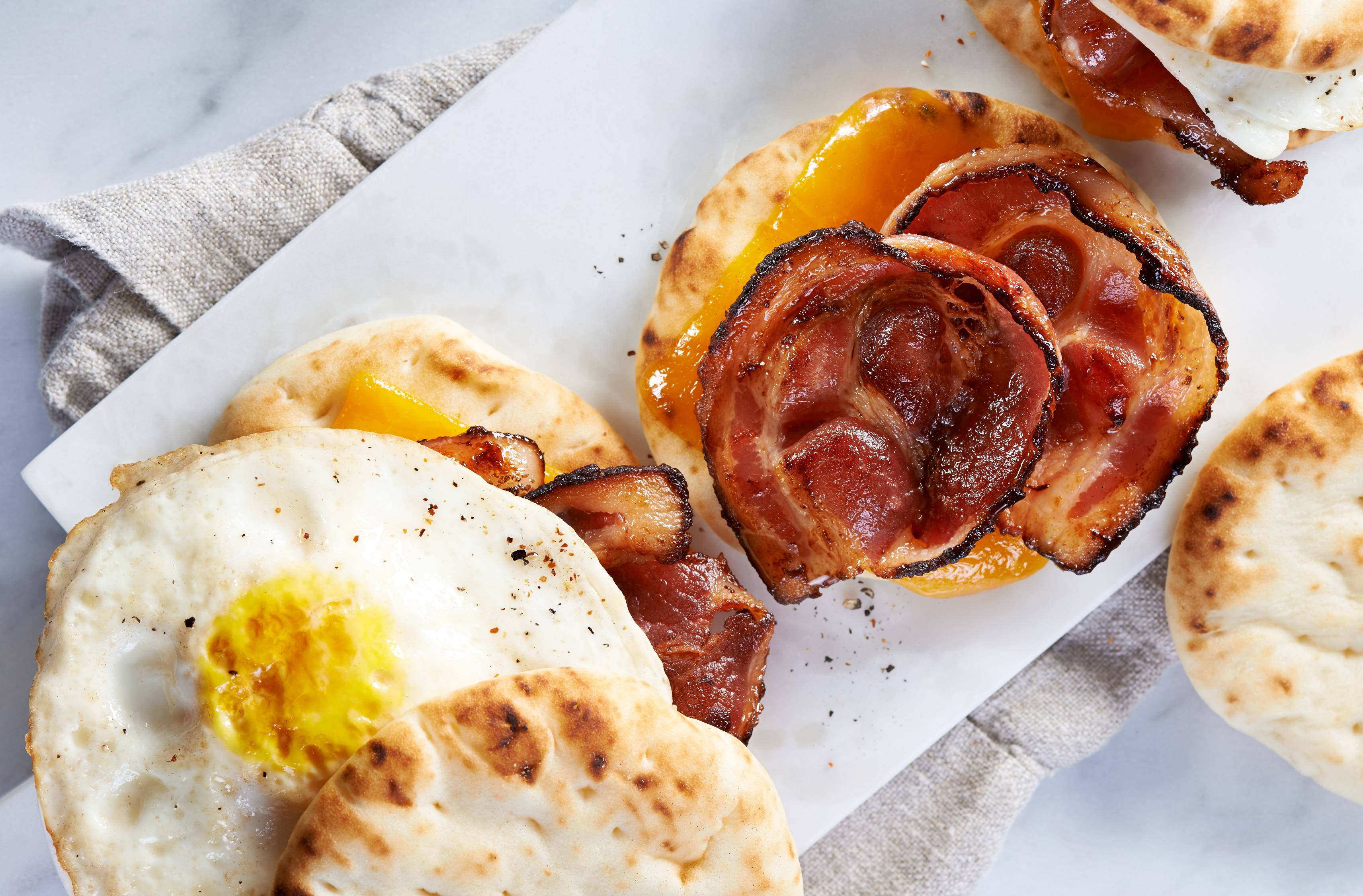 A breakfast sandwich on PC Naan Rounds with bacon, Cheddar & a fried egg

