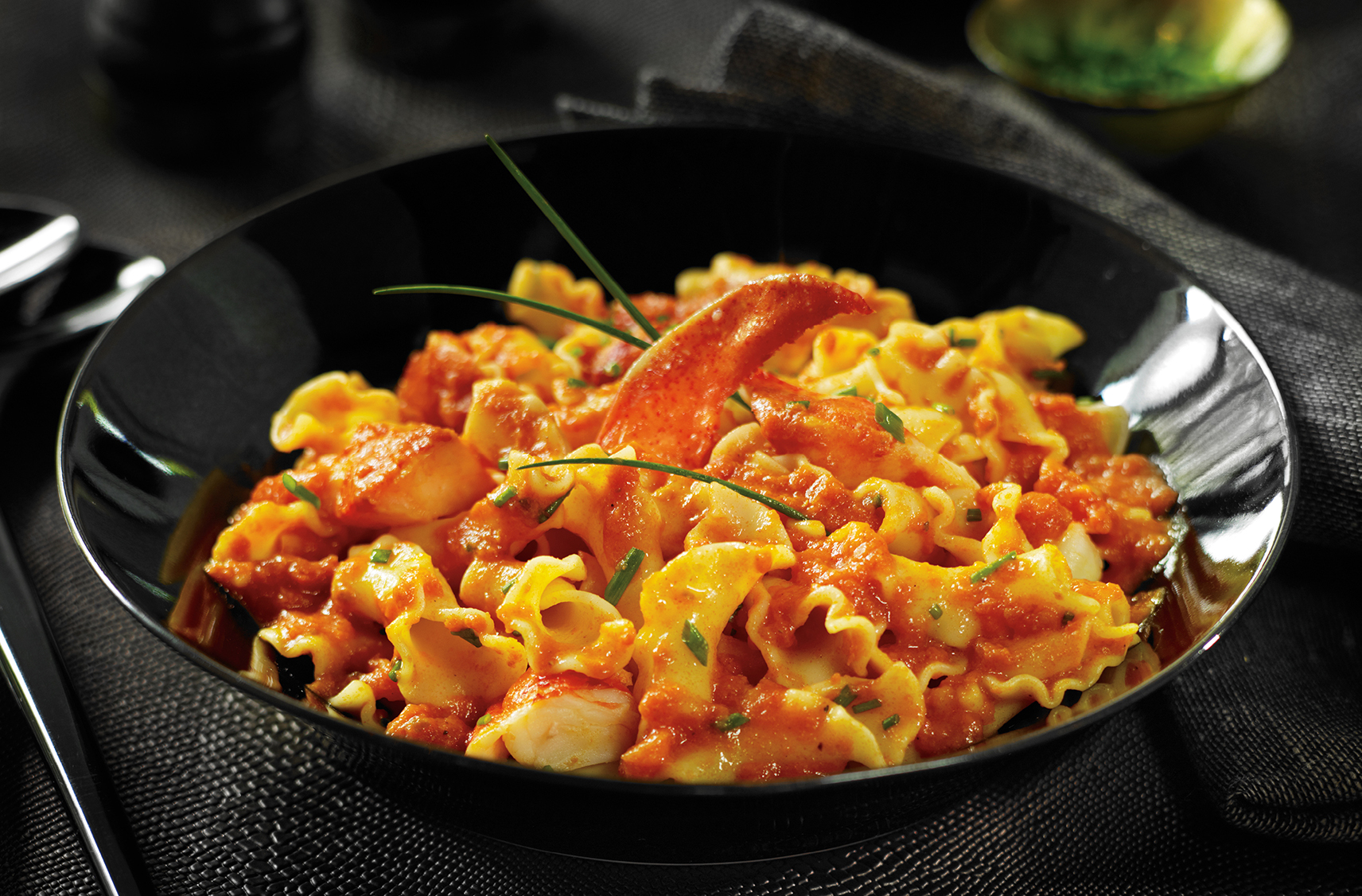 A bowl of fiorelli pasta with lobster pieces in a tomato-based vodka sauce