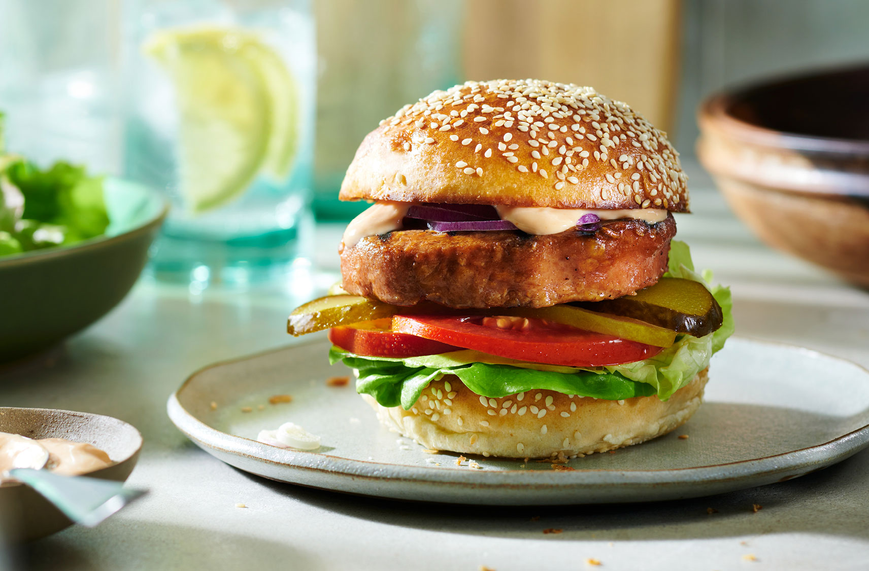 Un burger à base de plantes avec toutes les garnitures sur un pain recouvert de graines de sésame.