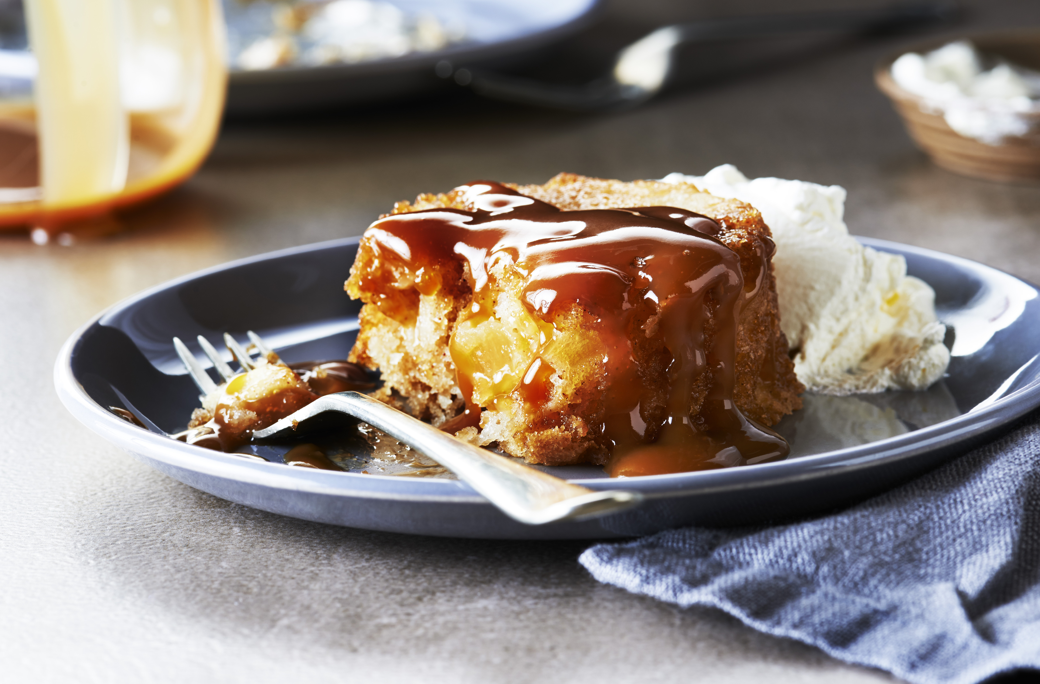 An individual apple cake on a dish covered in brandied dulce de leche sauce
