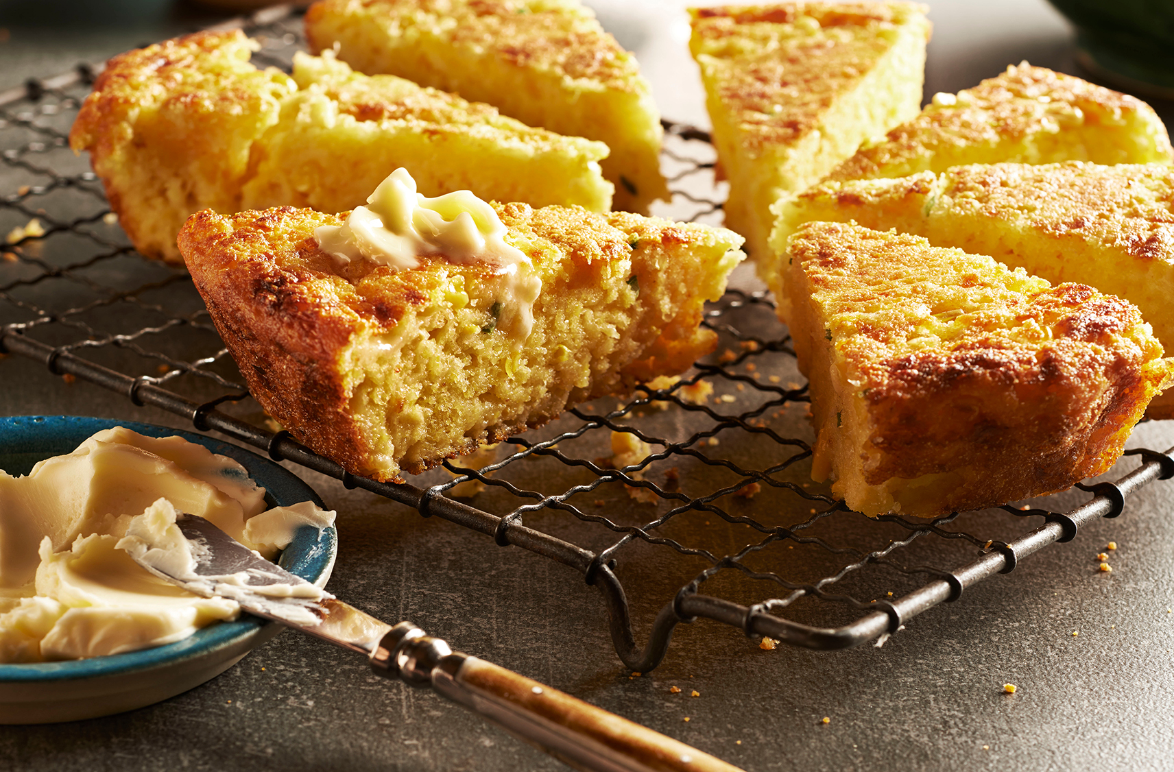 Wedges of fresh cornbread on a cooling rack slathered with butter