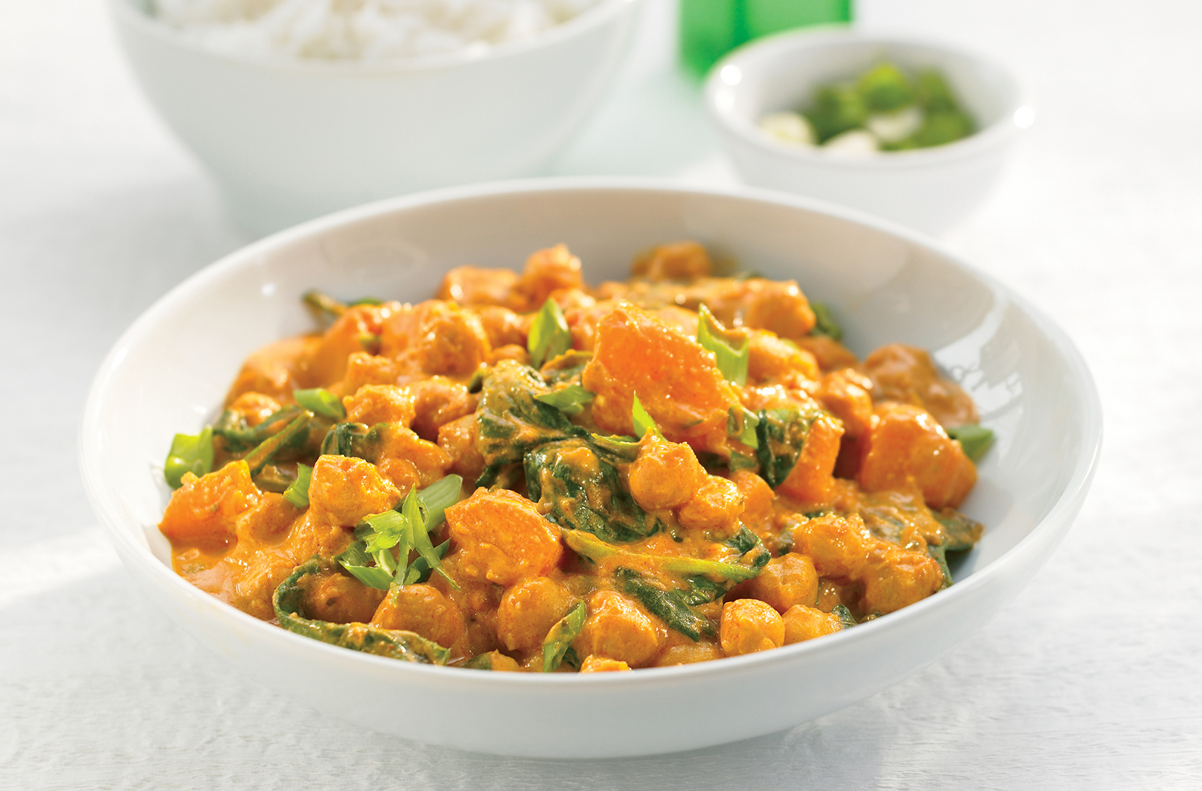 A bowl of curried chick peas & squash korma with spinach & green onions