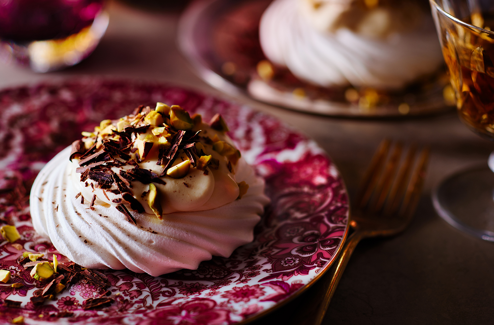 Meringue nests topped with devon cream, chocolate and chopped pistachio