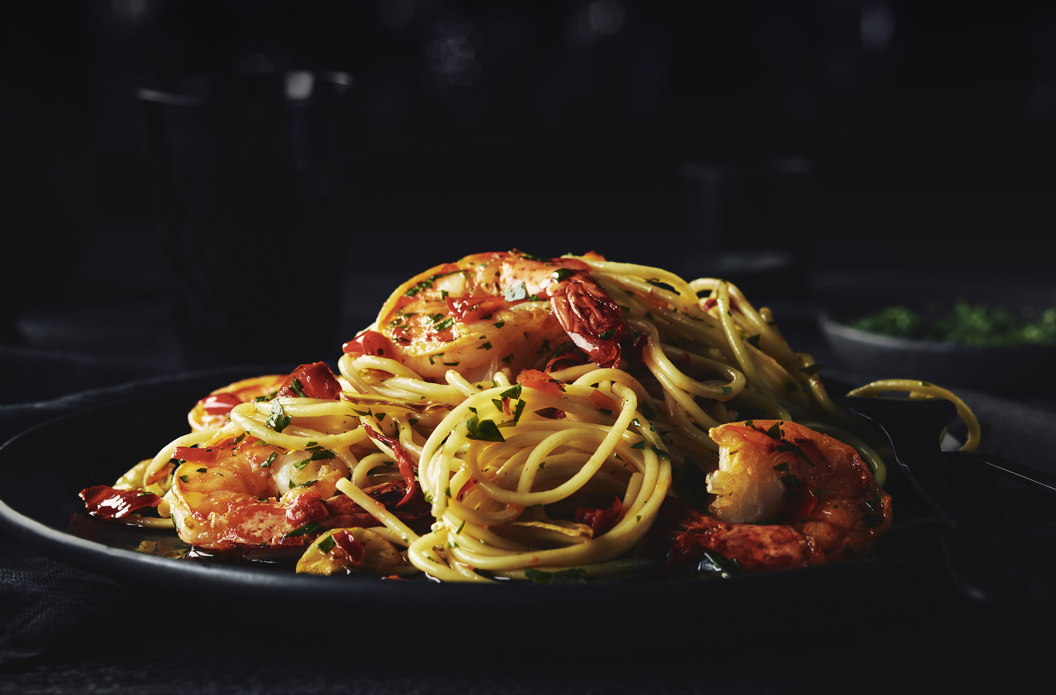 Shrimp cooked with peperoncini and spaghetti aglio e olio dish served on a plate
